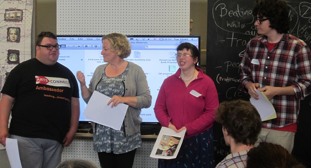 Four people standing in front of a screen giving a presentation of PhD research